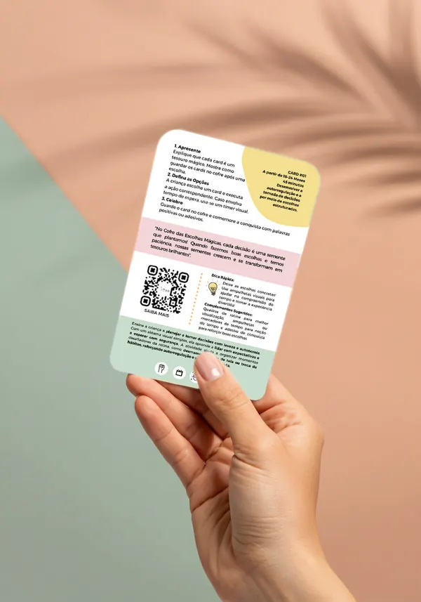 Mão segurando o verso de um card, com o passo a passo da brincadeira e um QR code